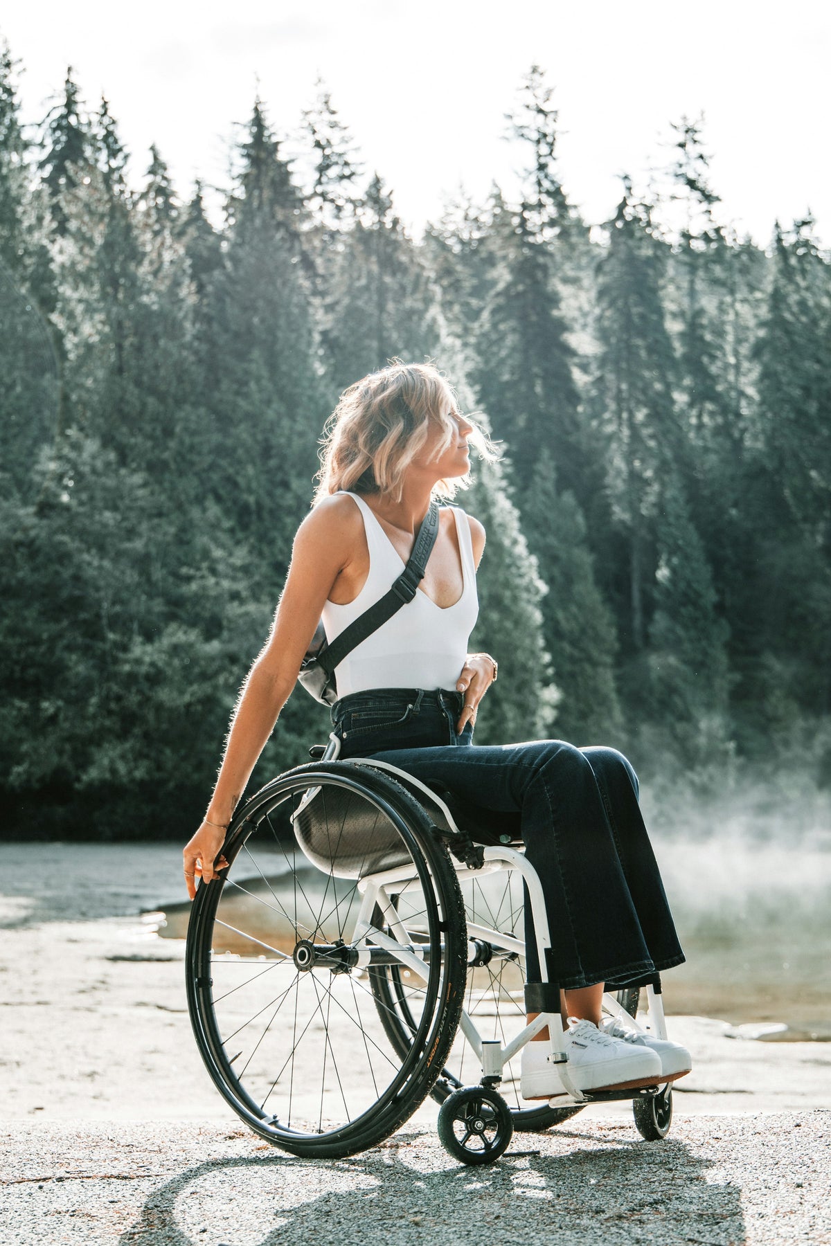 Woman using a wheelchair outdoors near trees in soft morning light